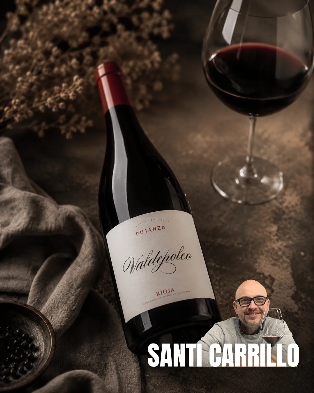 Botella de Pujanza Valdepoleo Rioja en una mesa junto a una copa y el sumiller Santi Carrillo